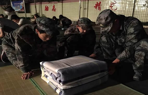 重慶三峽職業(yè)技工學(xué)校學(xué)生認(rèn)真地觀察教官疊軍被